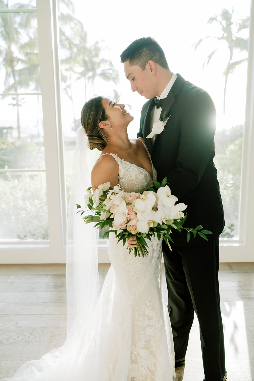 A bride and groom standing in front of a large window after their wedding at The Four Seasons