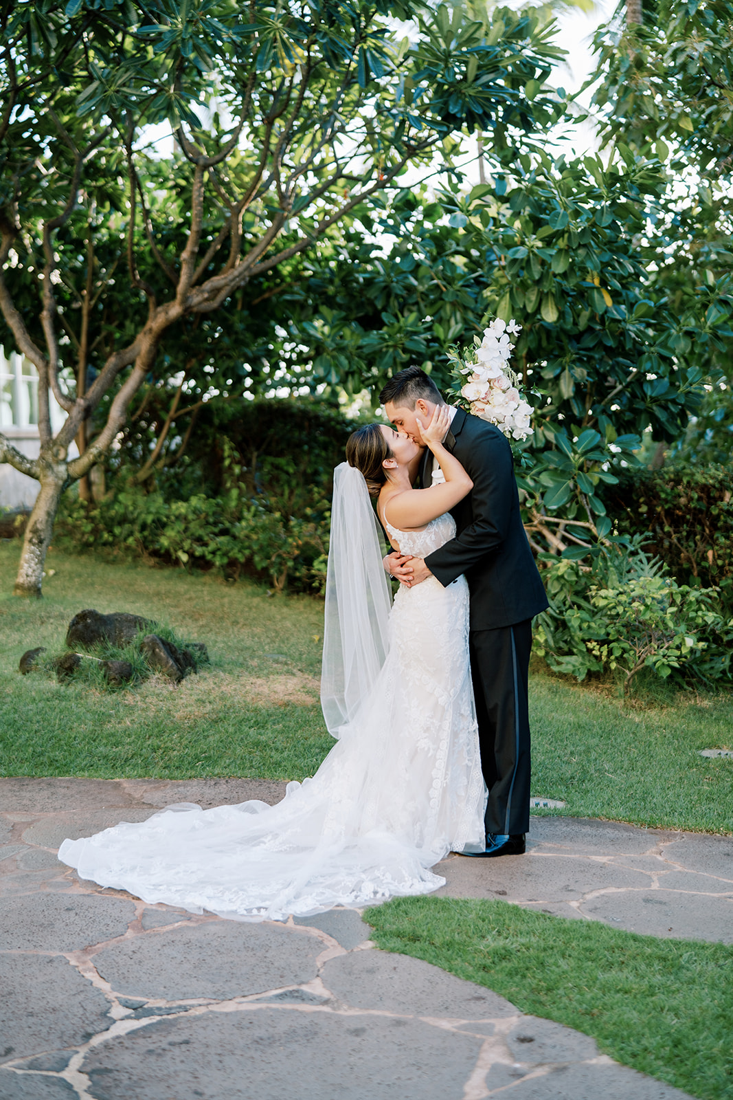 A bride and groom kissing in the garden at Ko'olina