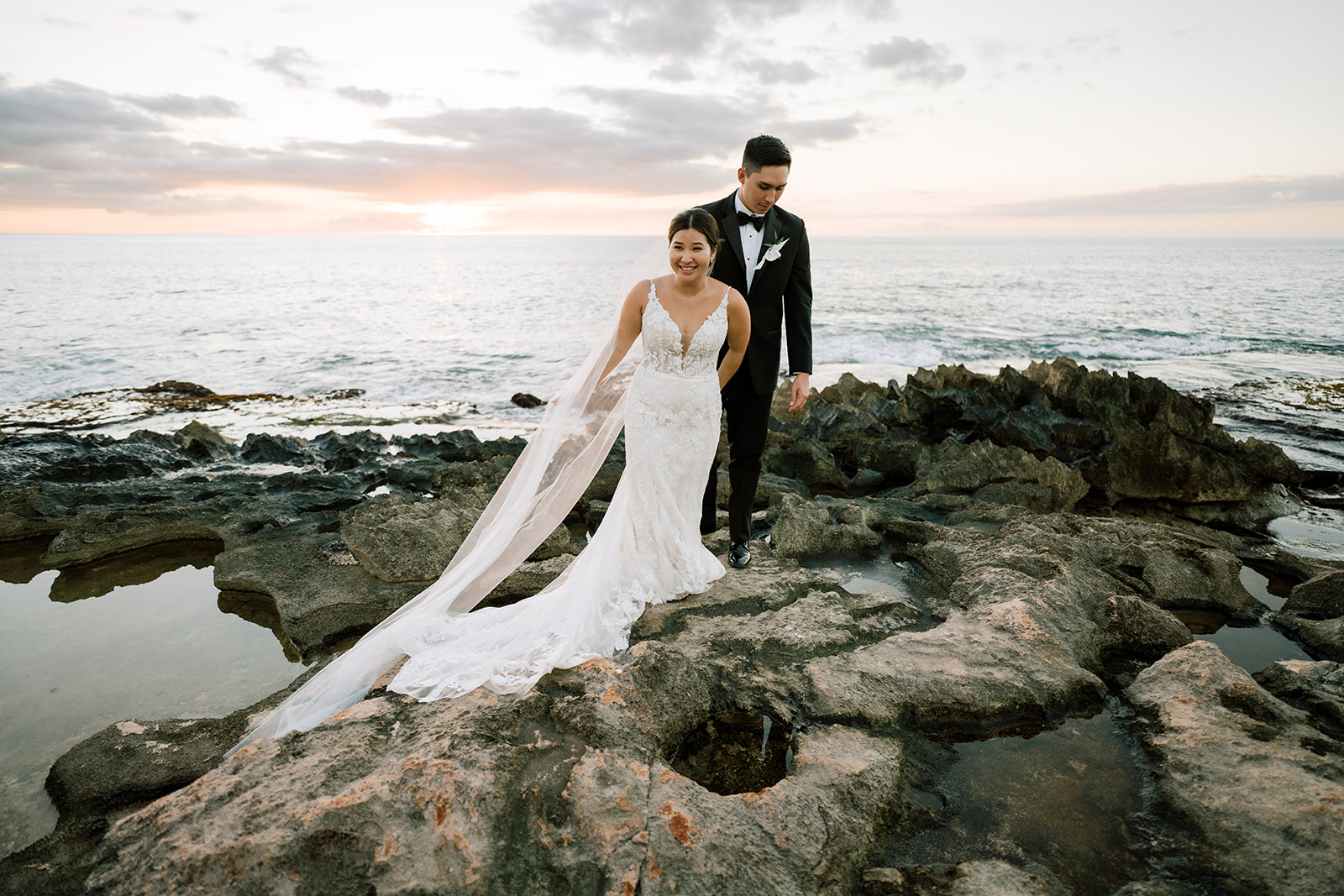 A bride and groom strolling by the Ko'olina Beach at Sunset