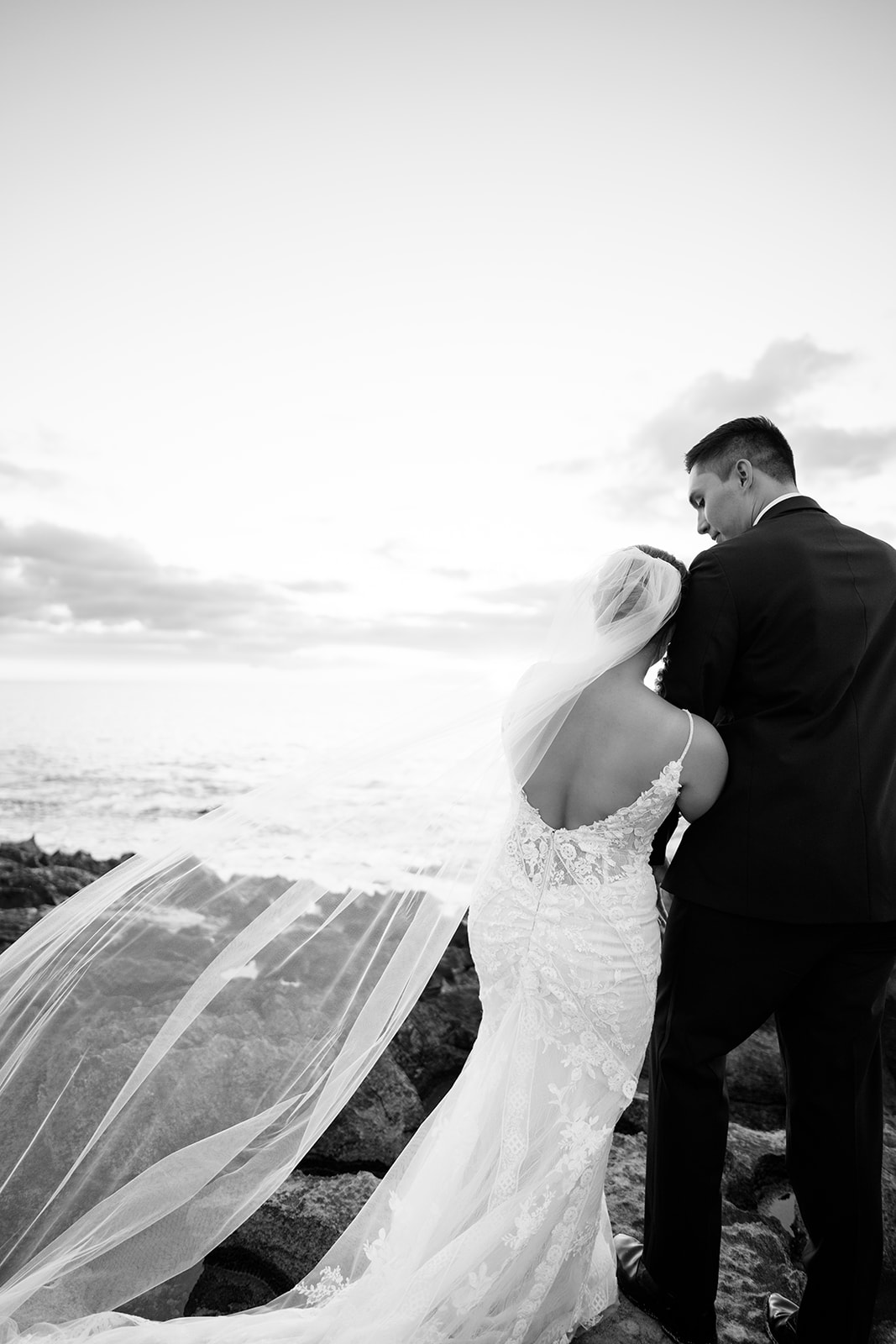 A bride and groom watching the sunset near the ocean The Four Seasons Resort Oahu captured by Megan Moura