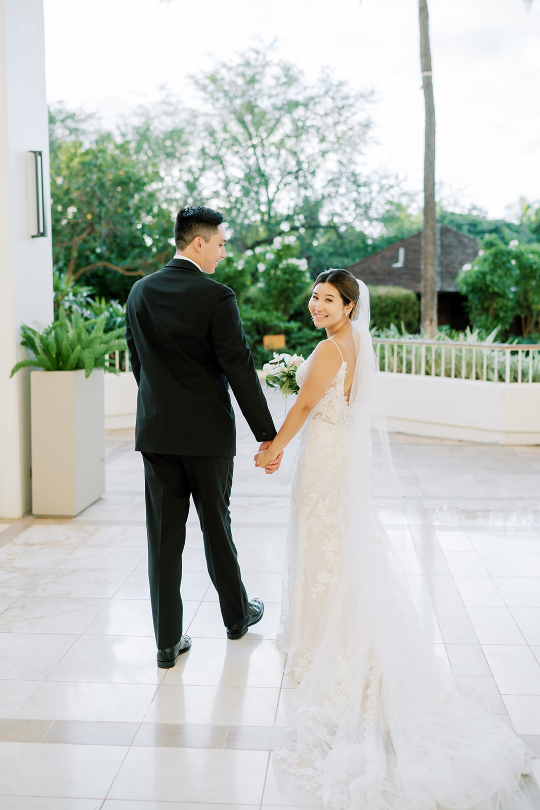 A bride and groom walking away from Megan Moura in the lobby of a hotel.
