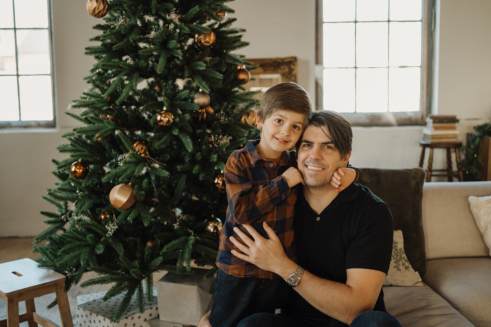 A dad and a boy by the Christmas Tree.
