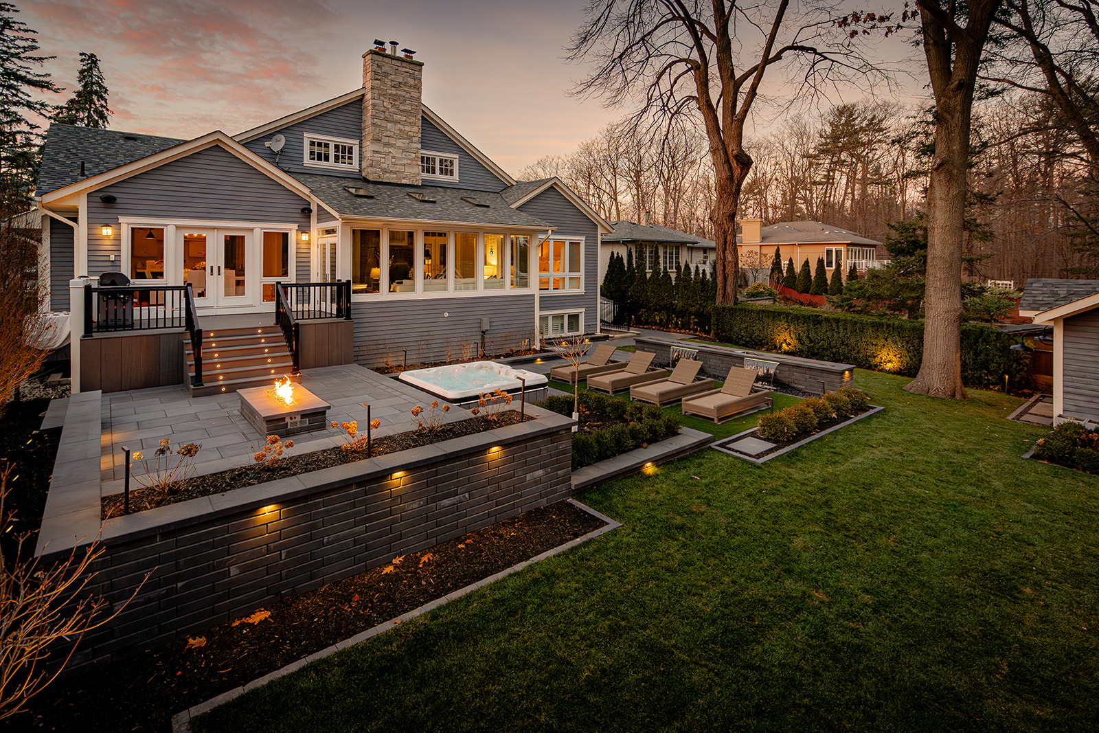 A backyard with lights on in the house.