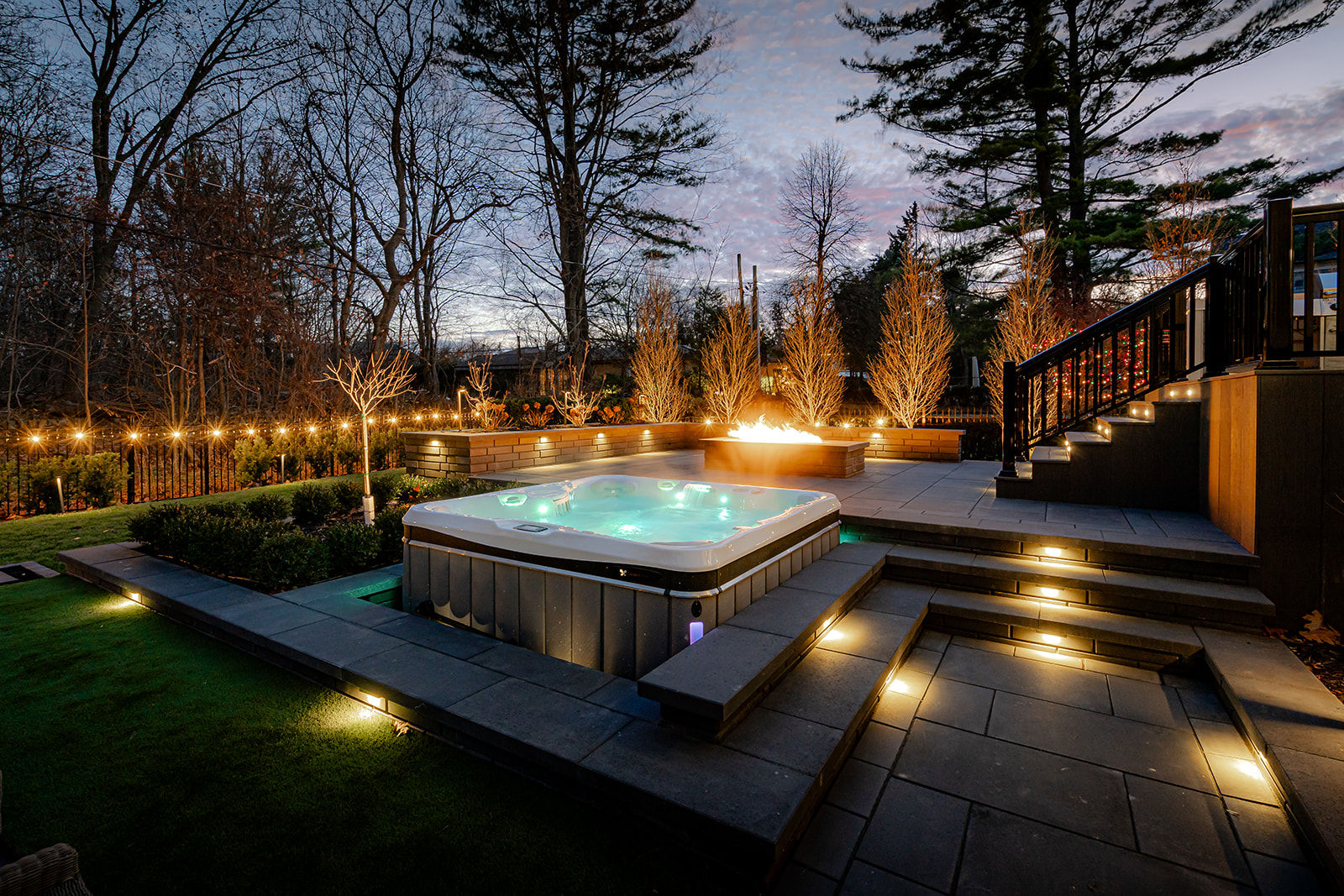 A fireplace and a jacuzzi with lounge chairs in the back yard.