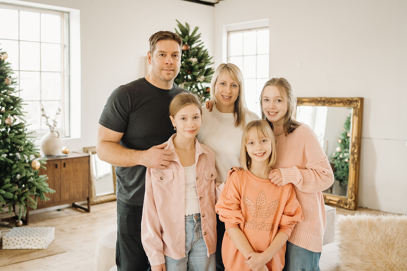 A family of five standing in front of a Christmas Tree.