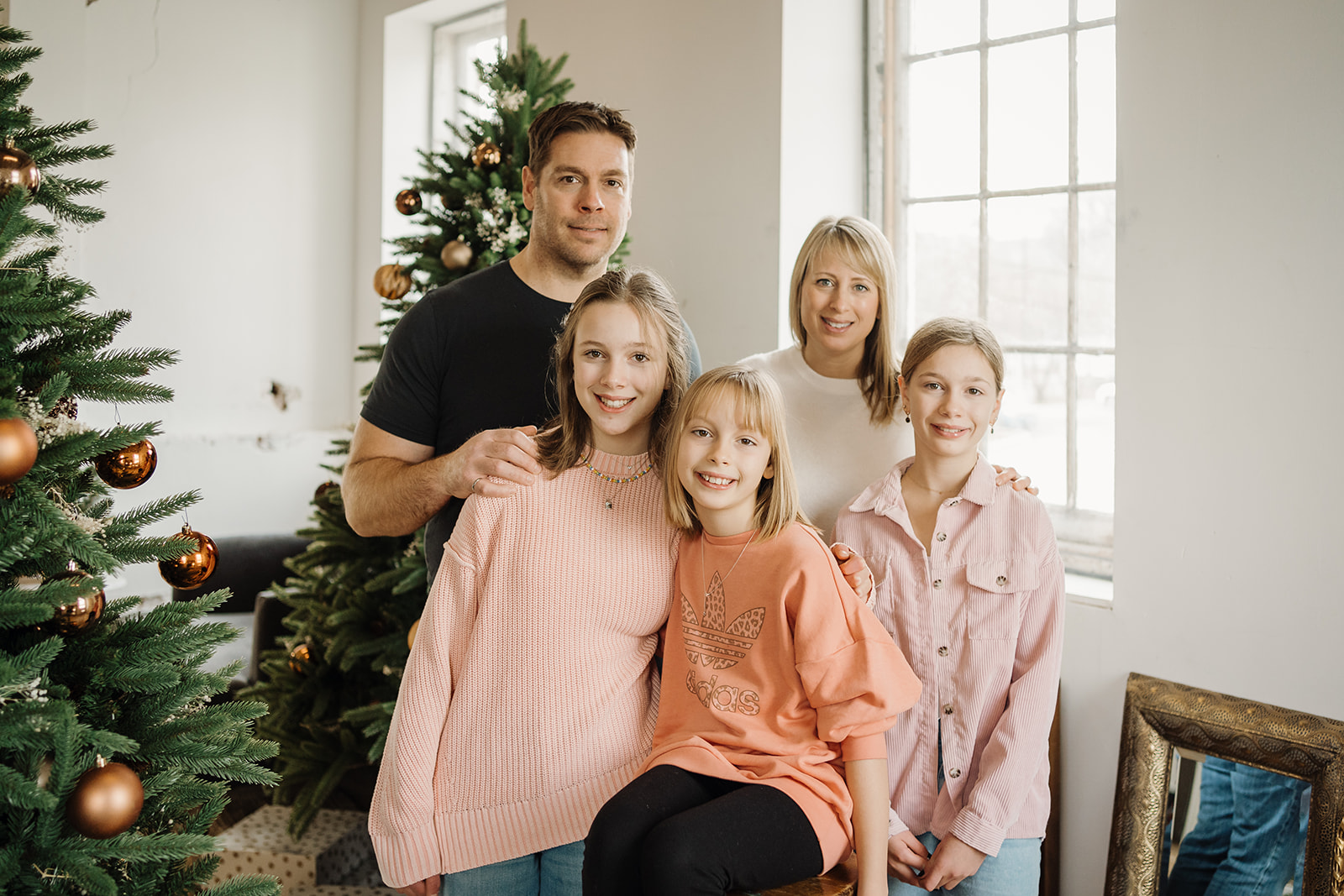 A family of five standing in front of a Christmas Tree.