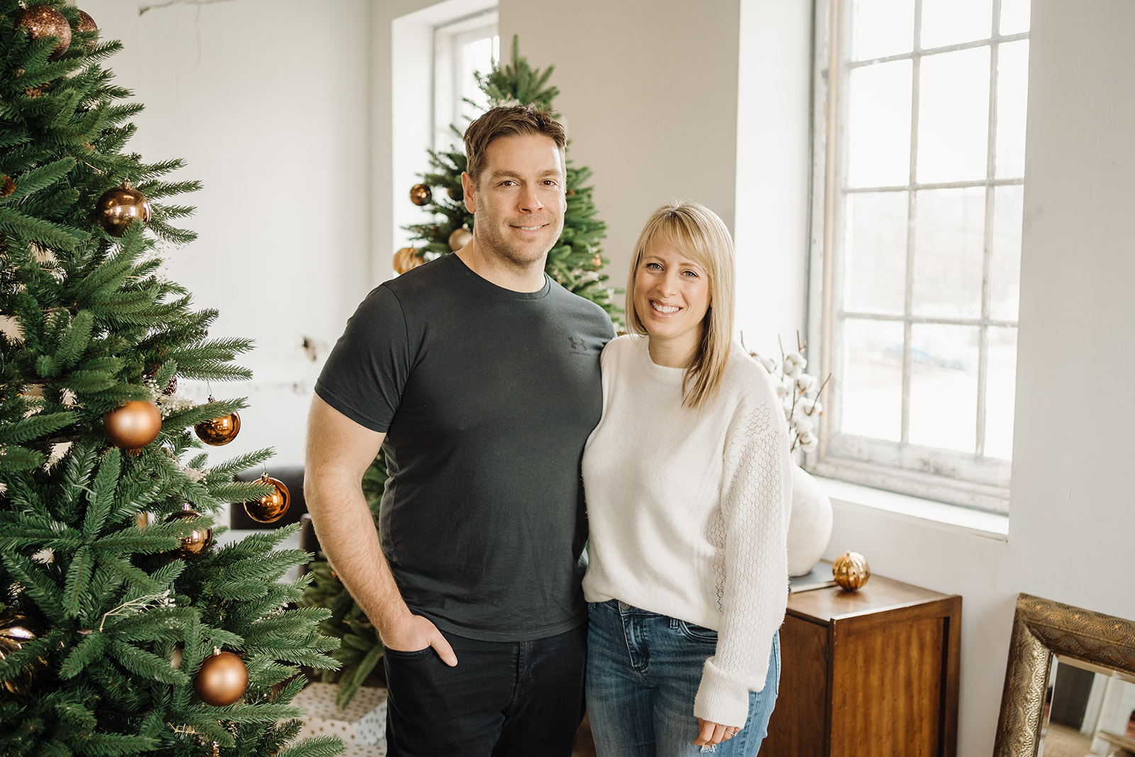 A man and woman standing beside a Christmas Tree.