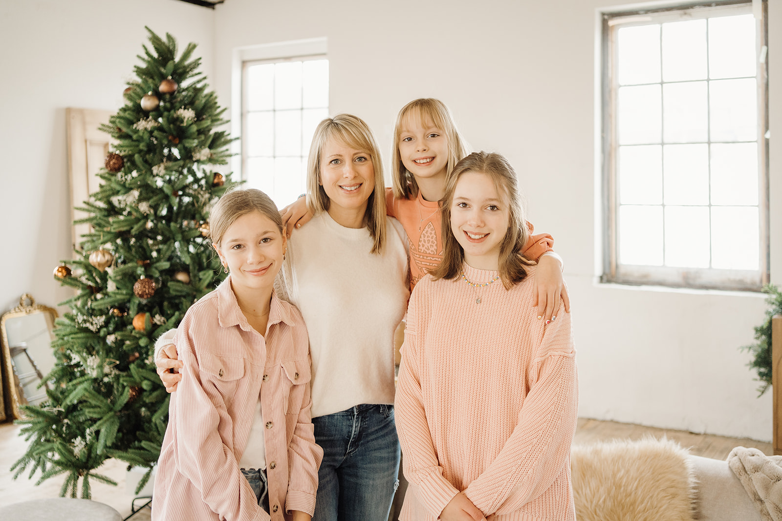 Three girls and a mother standing in front of a Christmas Tree.