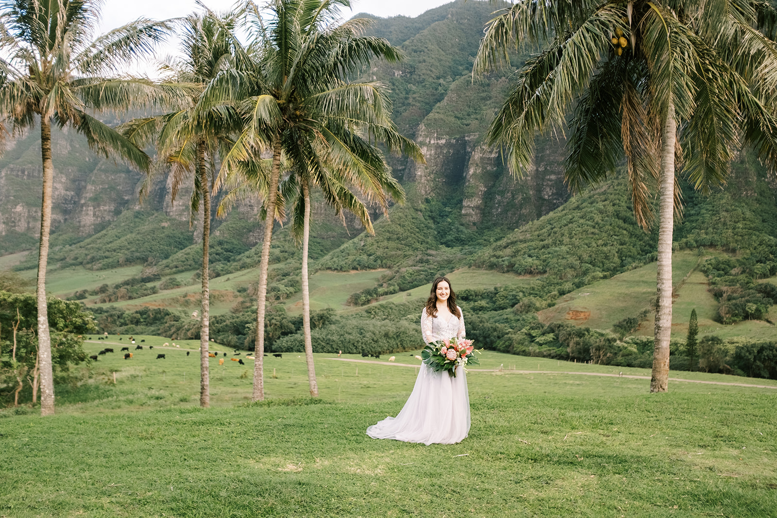 A bride in a white dress standing in front of palm trees.