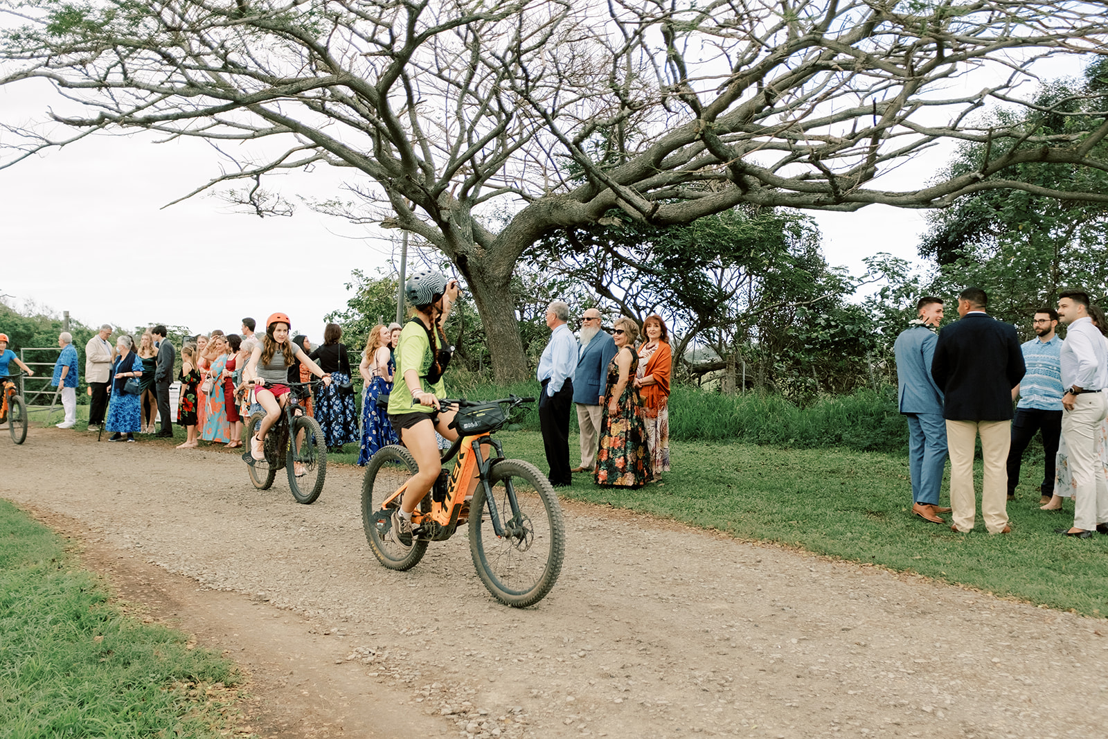 A group of people and a person riding a bike on a dirt road.