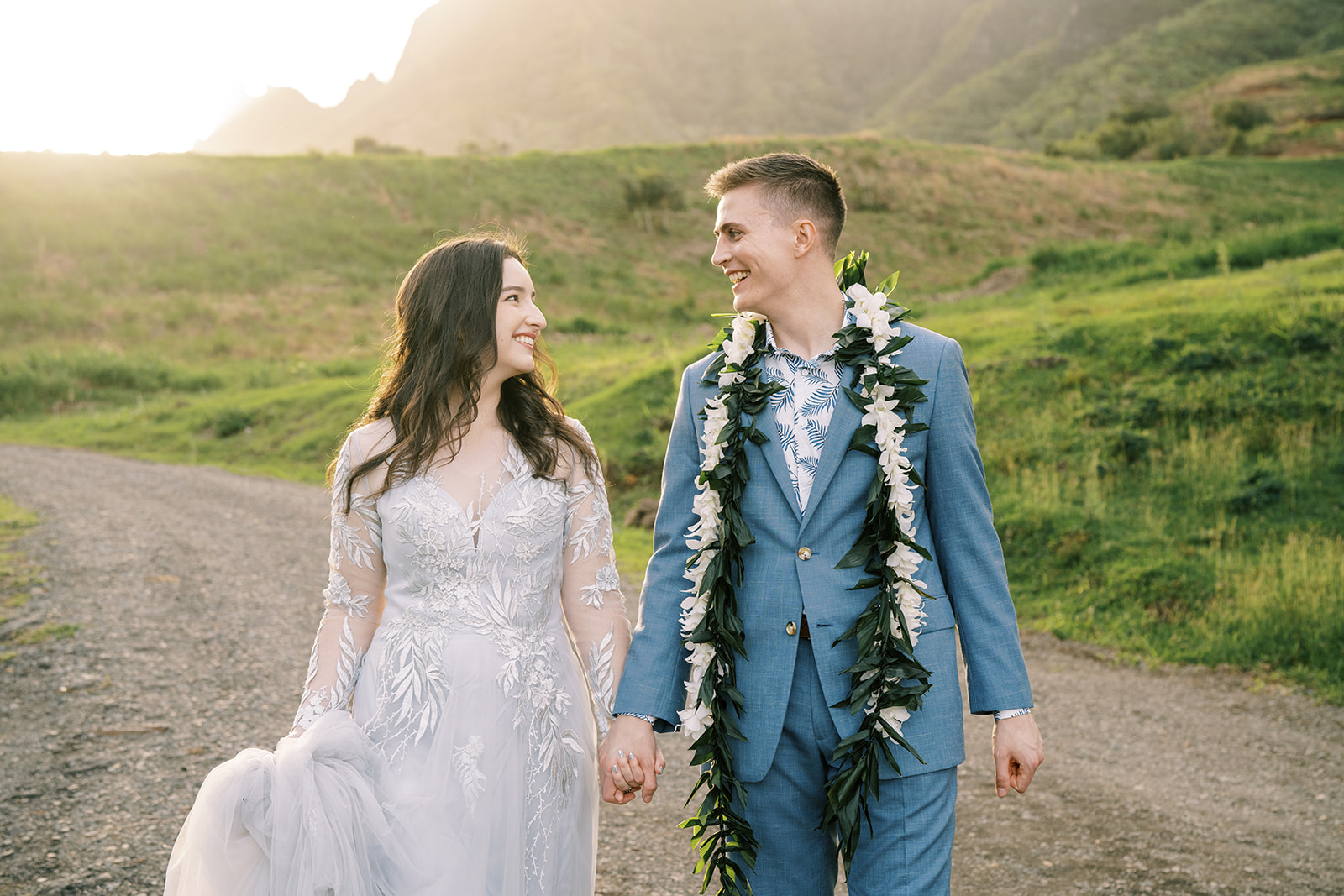 A bride and groom walking down a dirt road at a Kualoa Ranch Wedding in Hawaii.