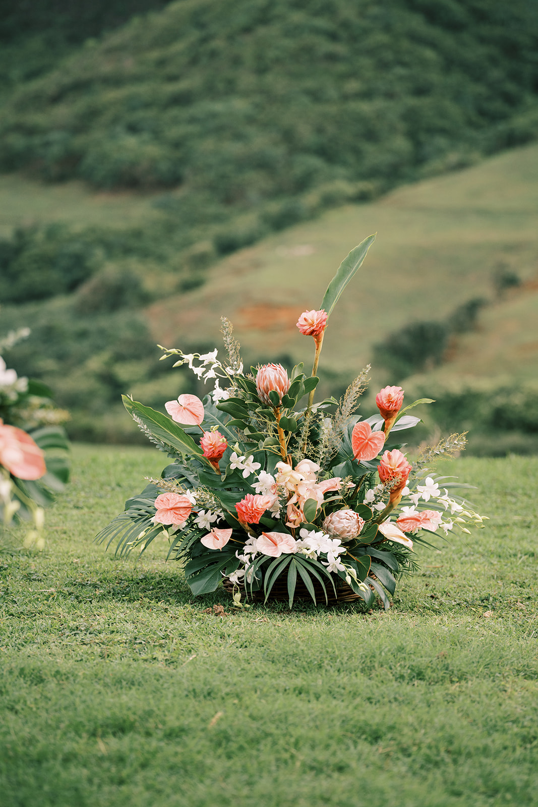 A large arrangement of flowers at Kualoa Ranch, a destination wedding venue, on a grassy field.