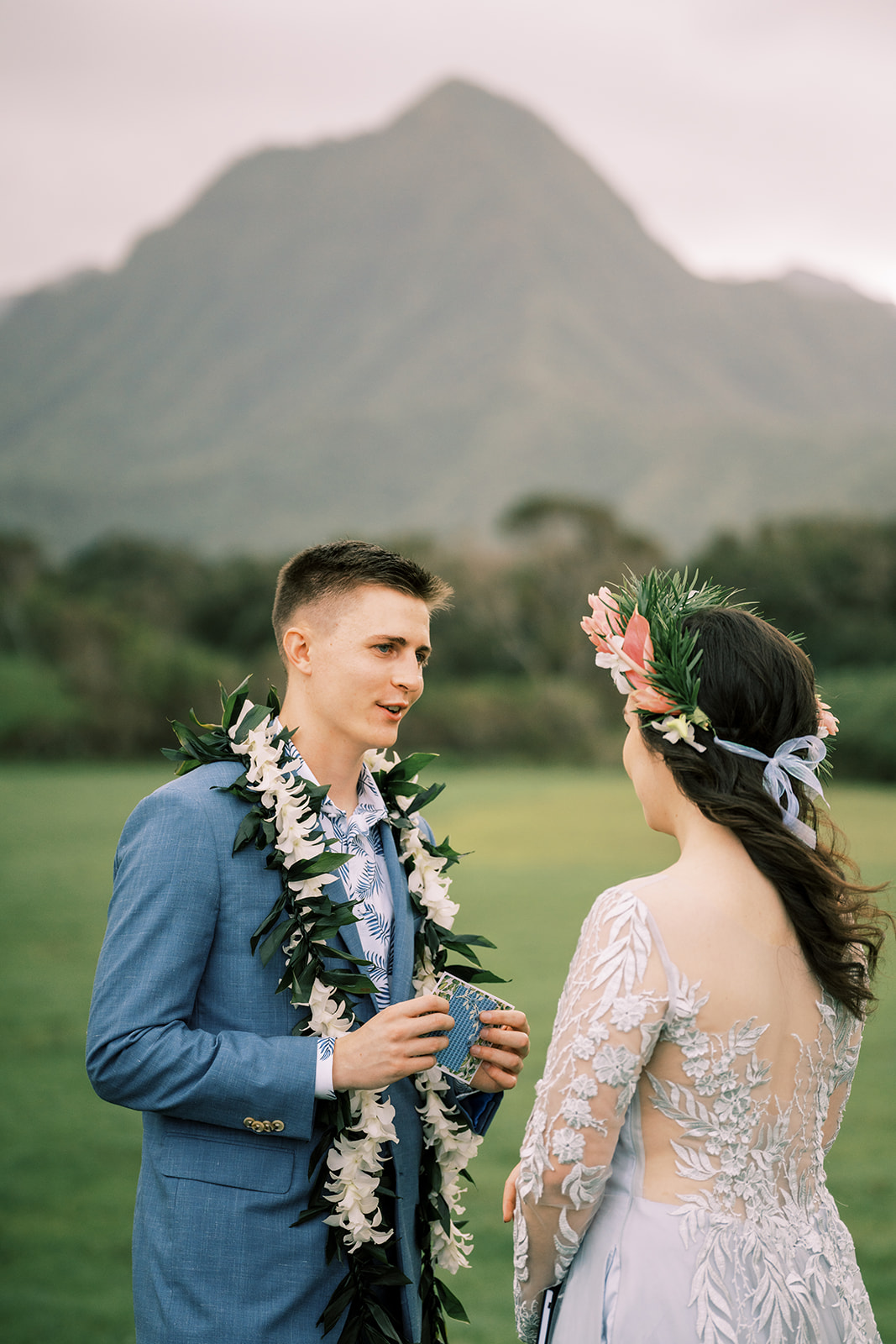 A bride and groom standing in front of a mountain at a Kualoa Ranch Wedding in Hawaii.