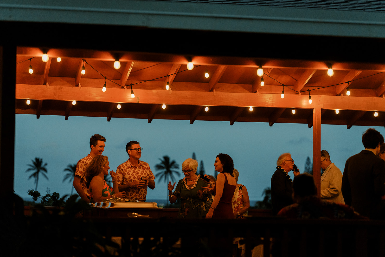 A group of people standing around a patio at dusk.