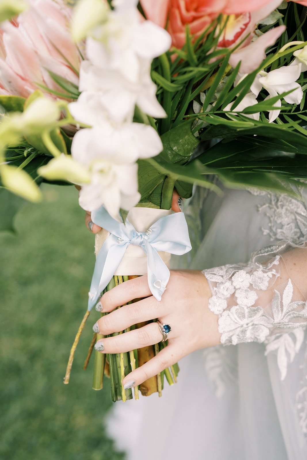 A bride holding a bouquet of pink and blue flowers.