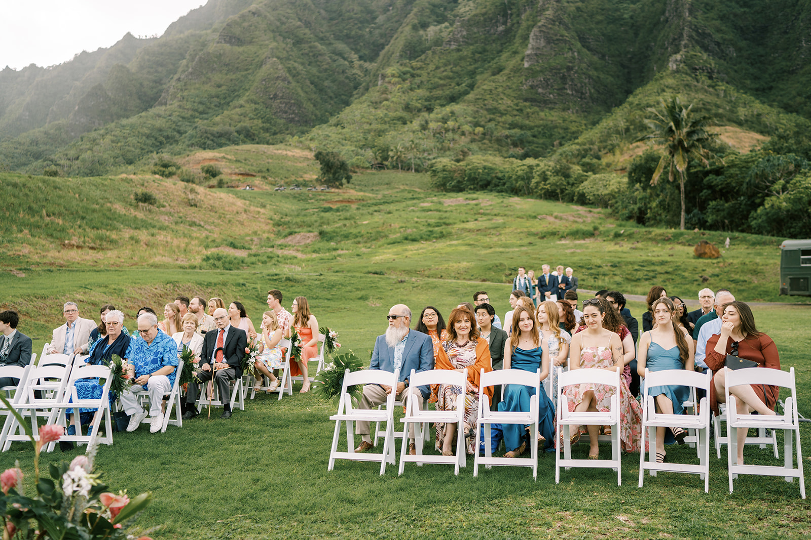 Hawaiian wedding ceremony in a field with mountains in the background.
