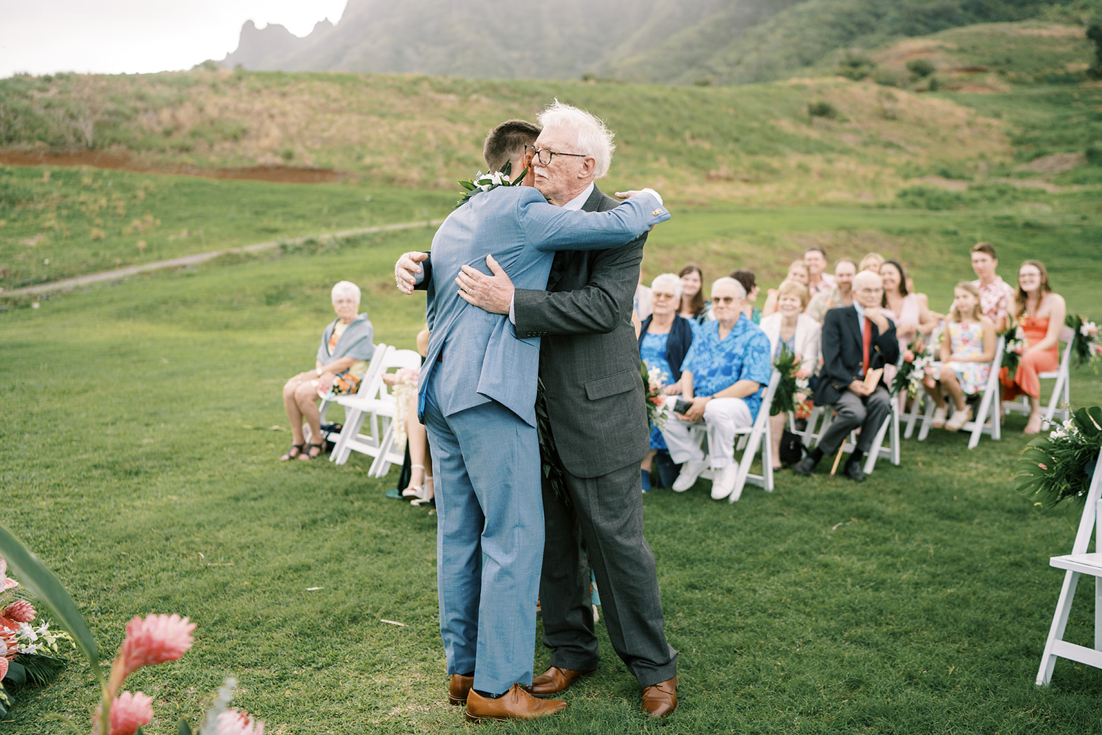 A man hugging his father during a wedding ceremony.