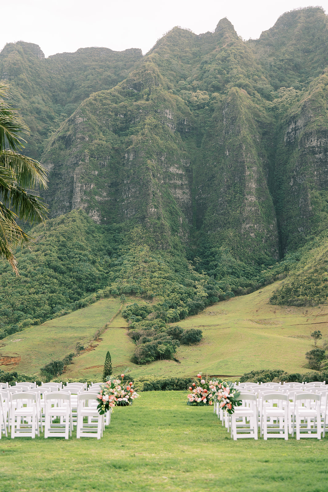 A Destination Wedding ceremony set up in the grass with mountains in the background at Kualoa Ranch.