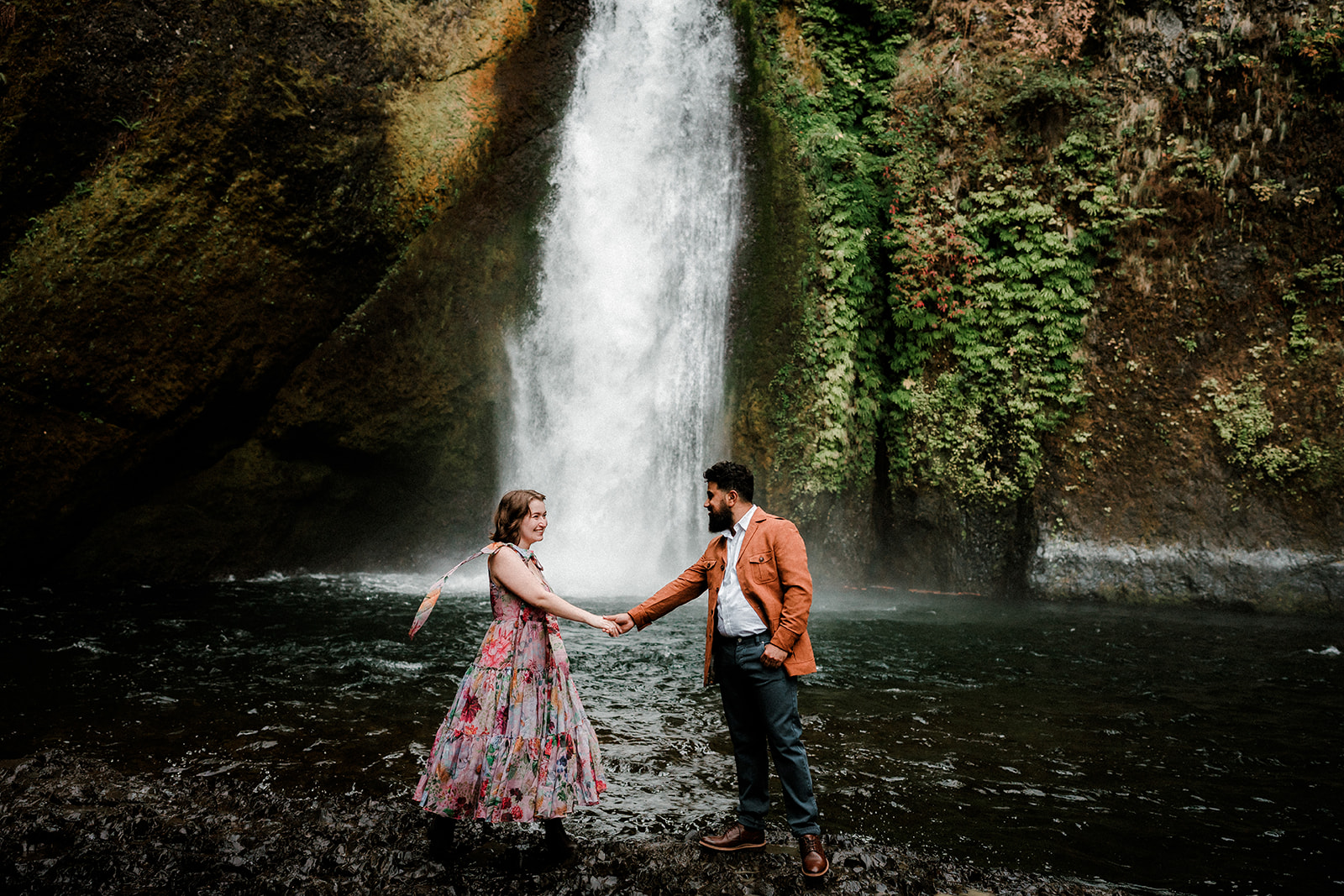 engaged couple embracing at the base of Wahclella Falls in the Pacific Northwest