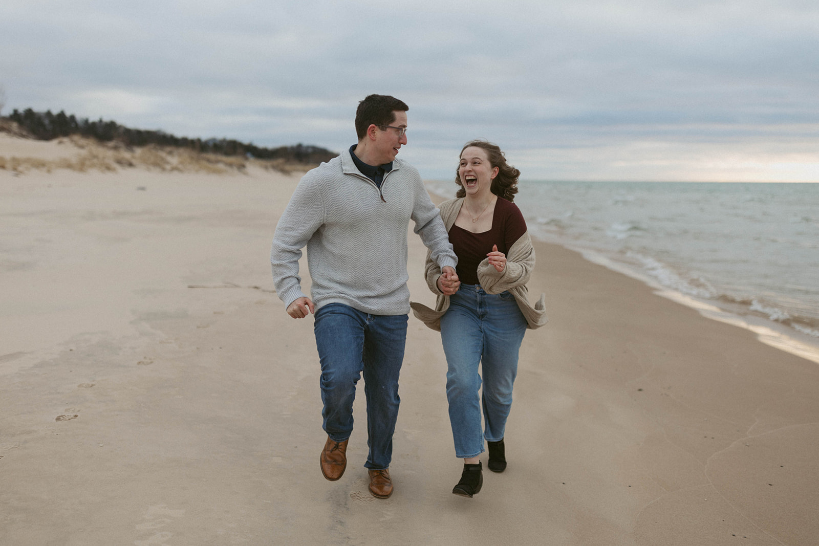 Couple running along the beach at Little Sable Lighthouse in Mears, Michigan.