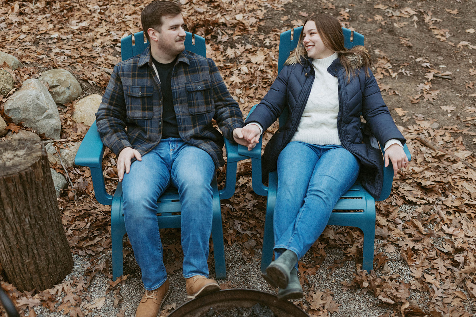 Couple sitting around a campfire during their unique engagement session