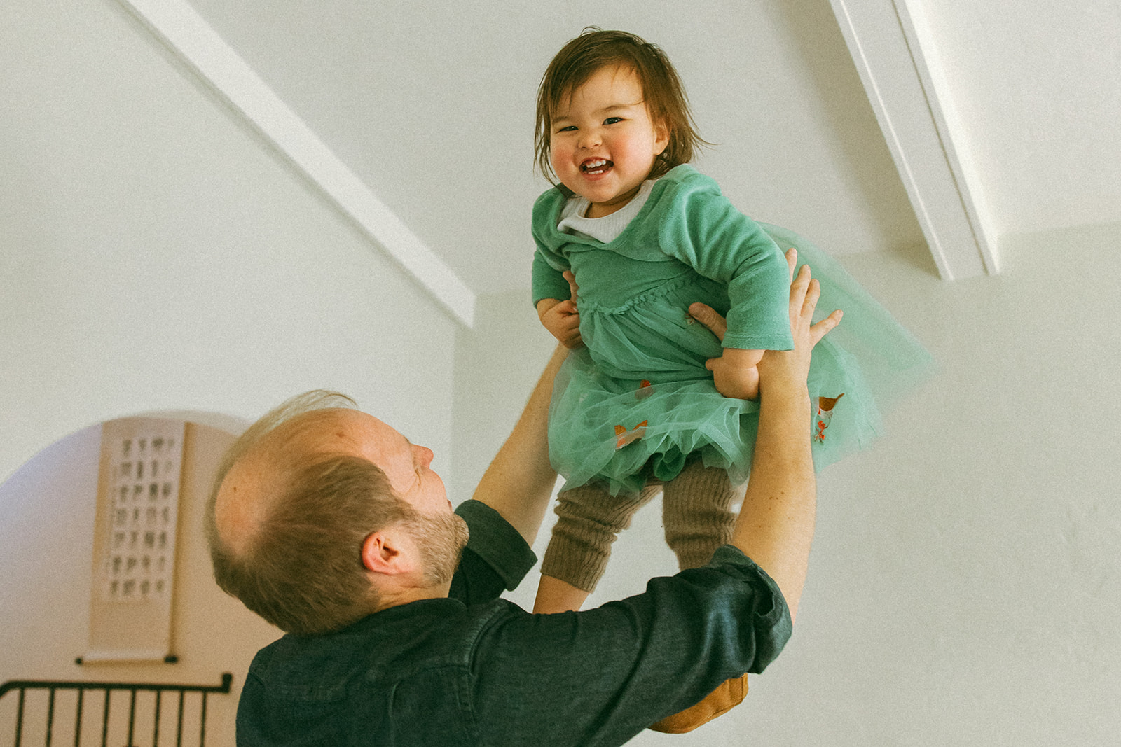 dad throwing adorable baby in the air at home