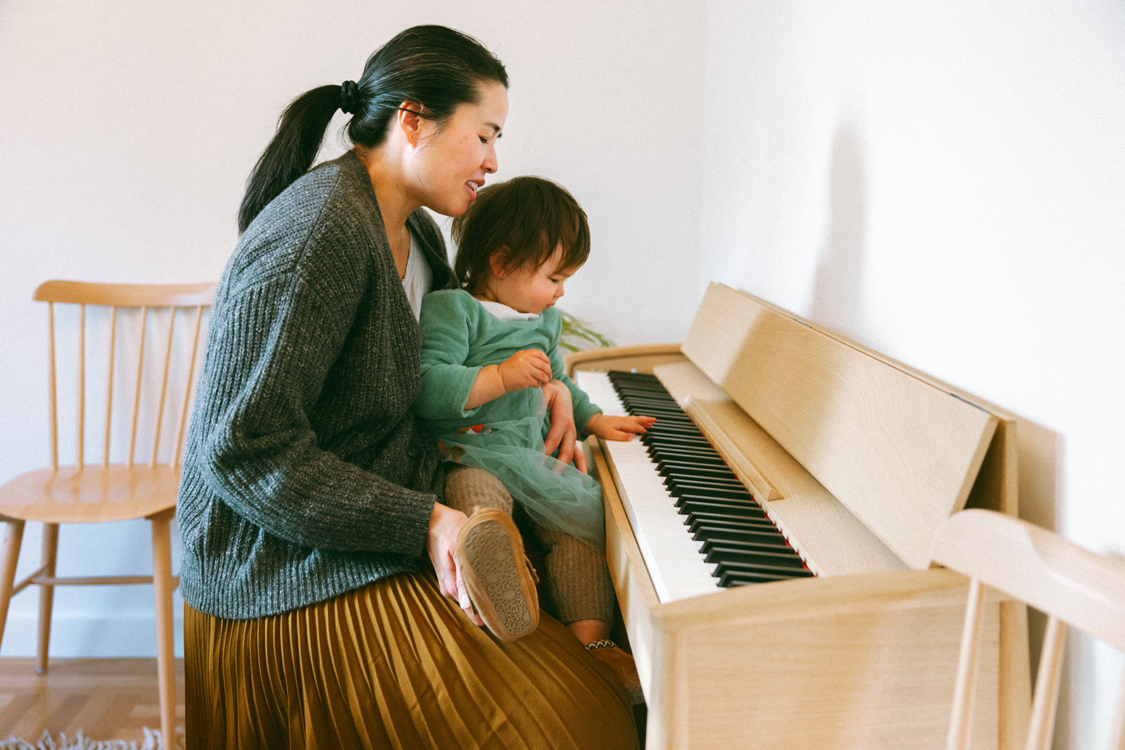 asian mom and baby playing piano