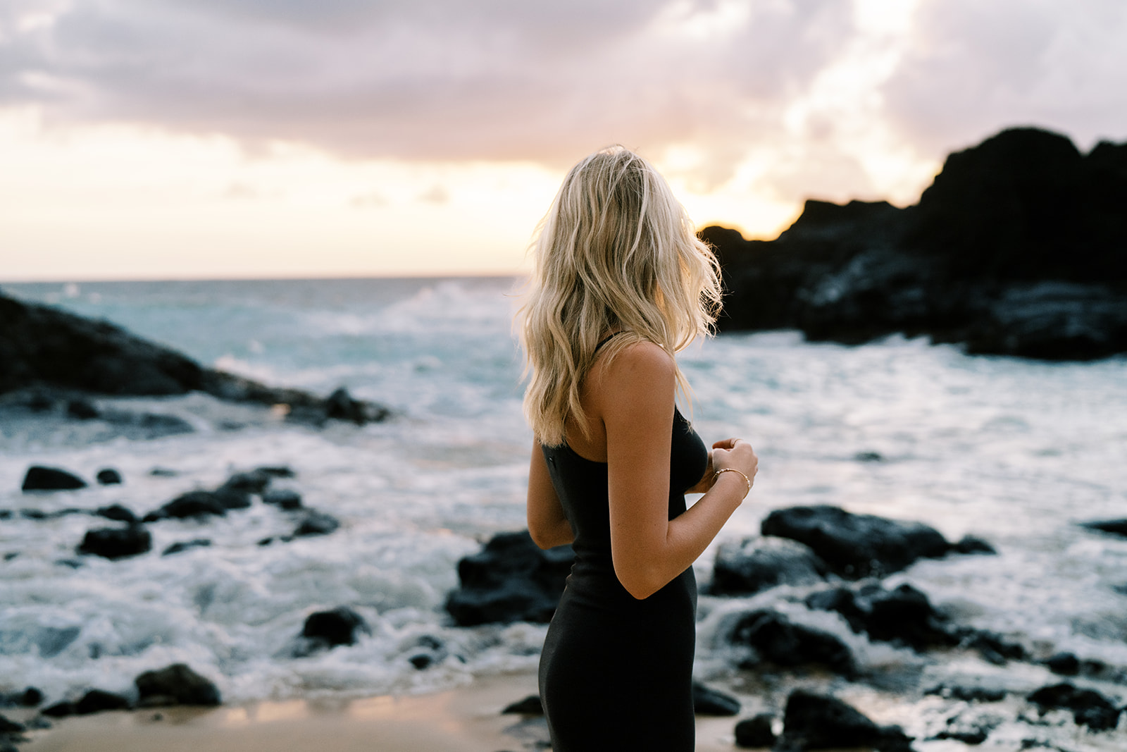 Woman by the seaside with her back on the camera captured by Hawaii senior portrait photographer Megan Moura