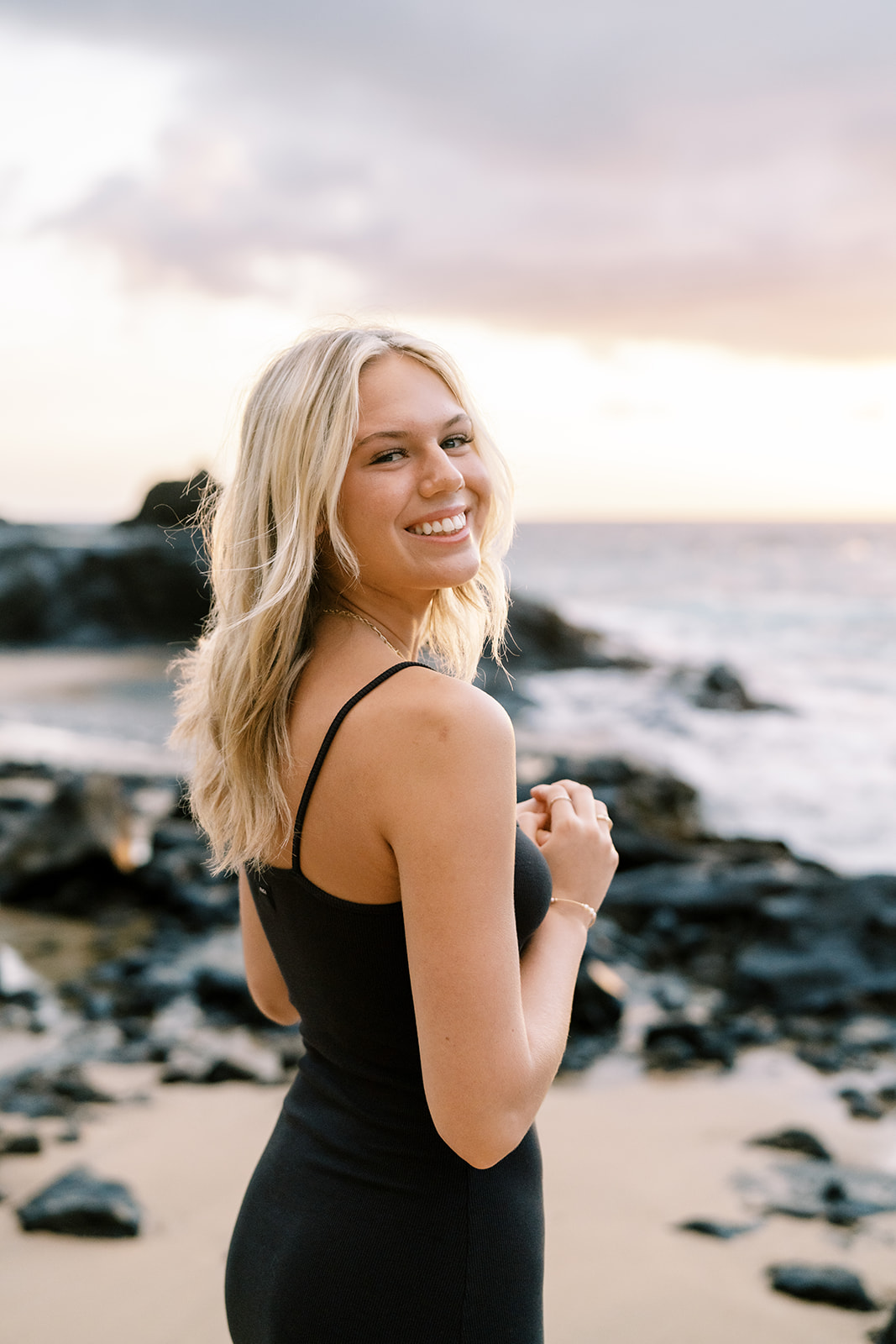 Young woman smiling on the beach at sunrise, captured by Hawaii senior portrait photographer Megan Moura.