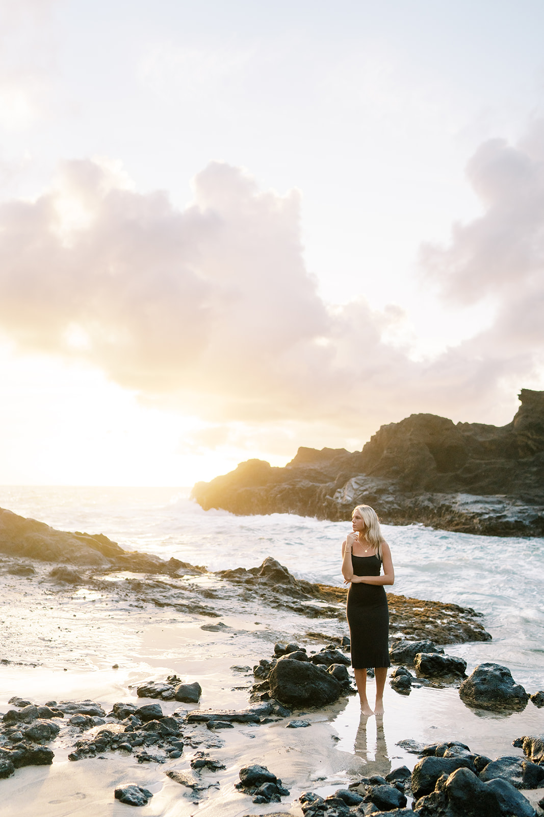 Woman standing on a rocky shoreline gazing at the Sunrise over the ocean high school senior portrait in Oahu