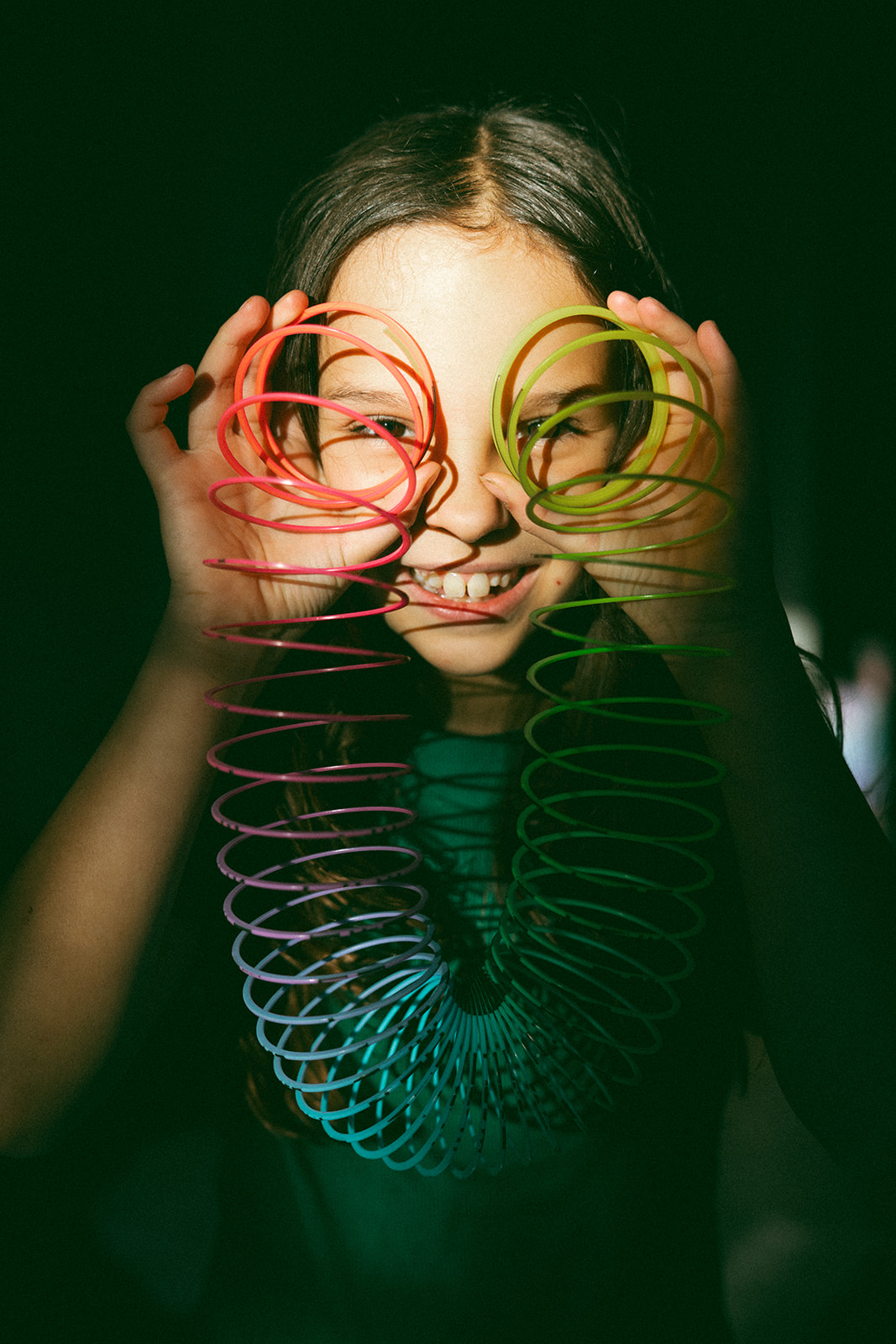 young girl holding slinky ends in front of her eyes like glasses