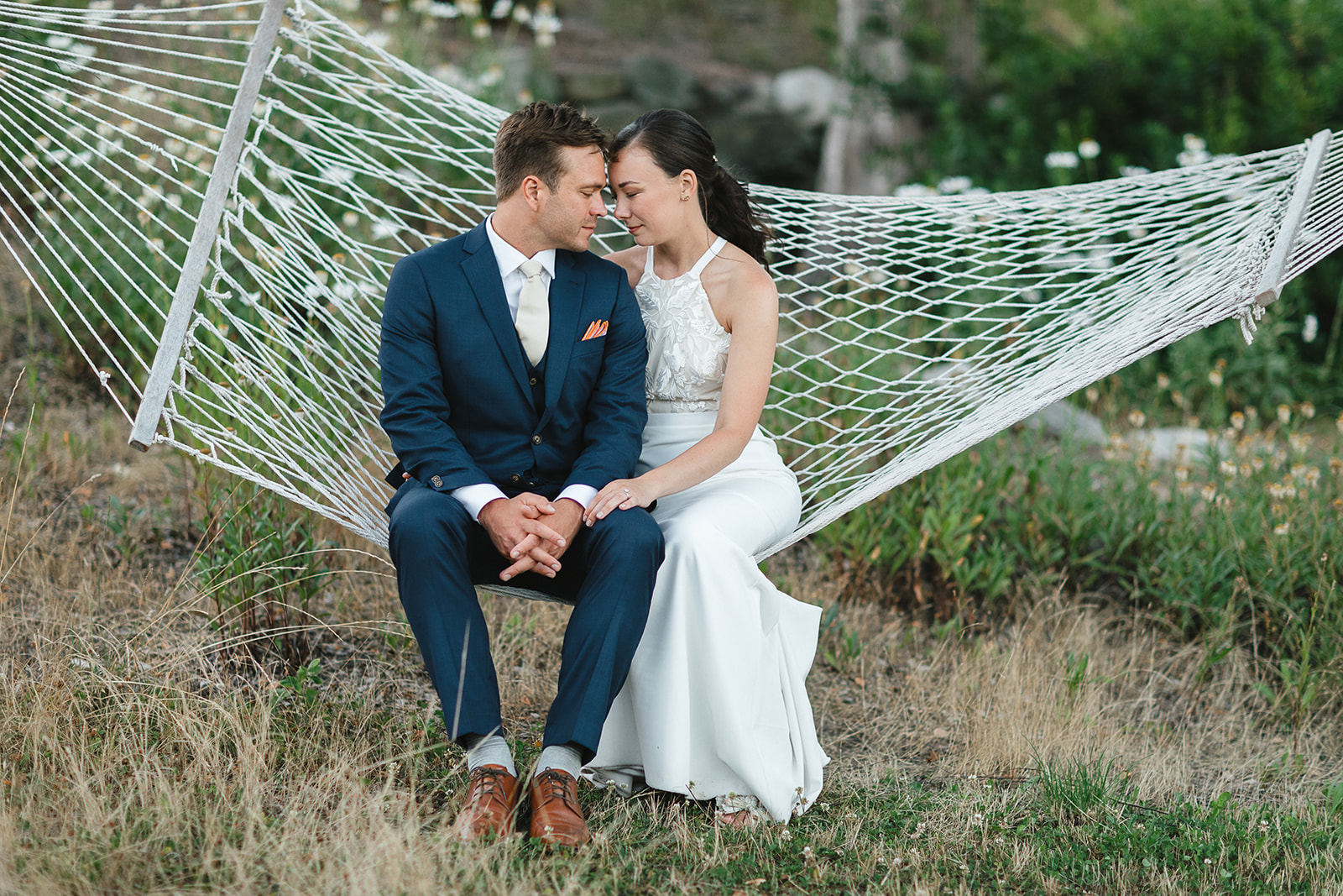 Bride and groom sharing a quiet moment sitting on a hammock.