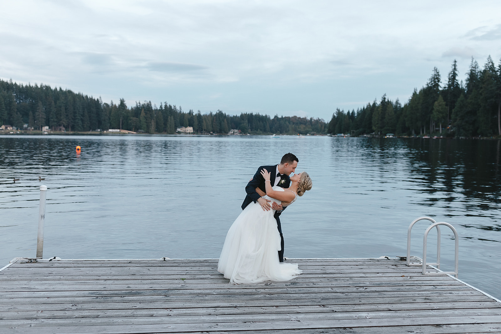 Groom dipping the bride on dock at Green Gates at Flowing Lake in Snohomish.