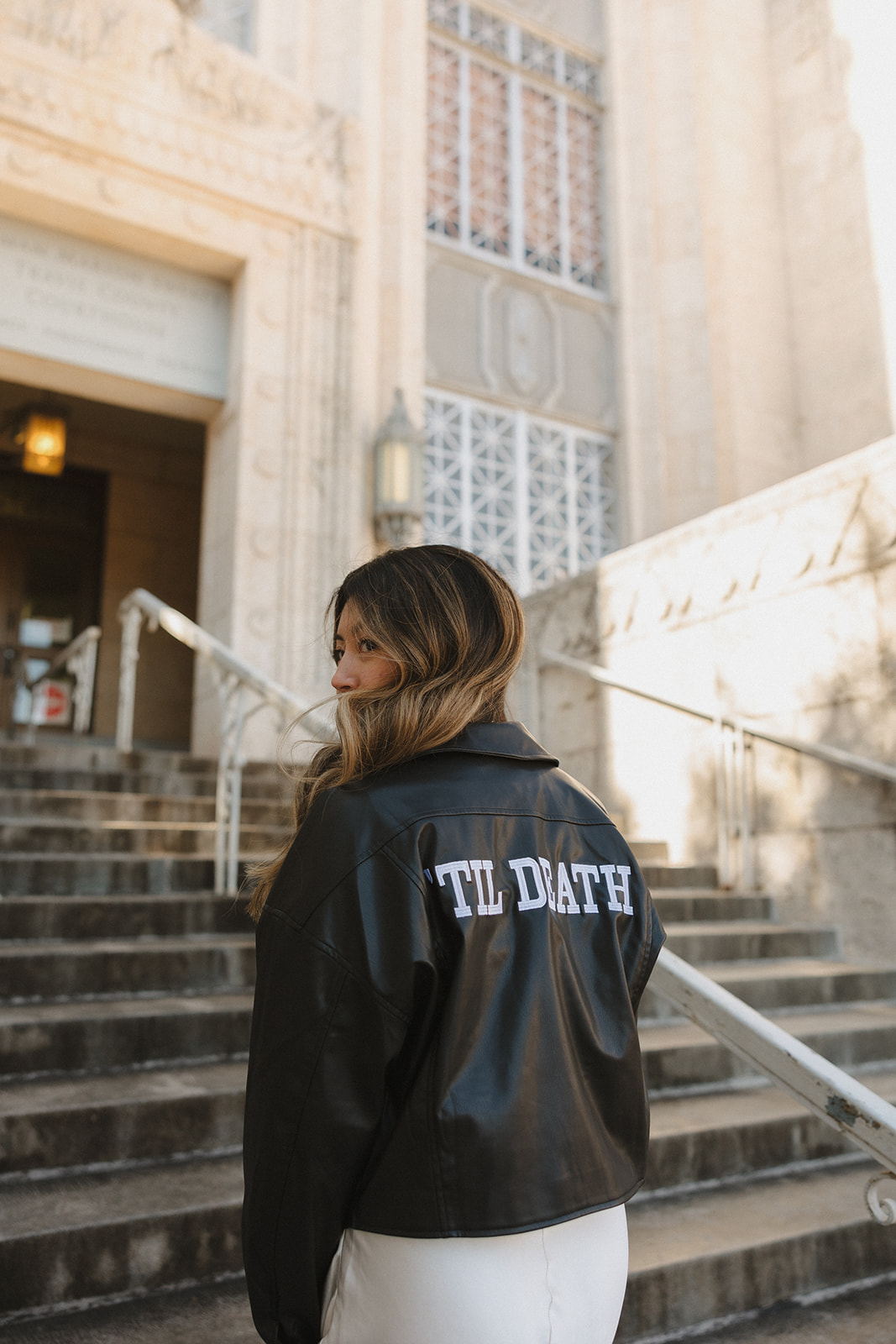 bride standing outside wearing a leather jacket of the courthouse after their elopement in downtown Austin 