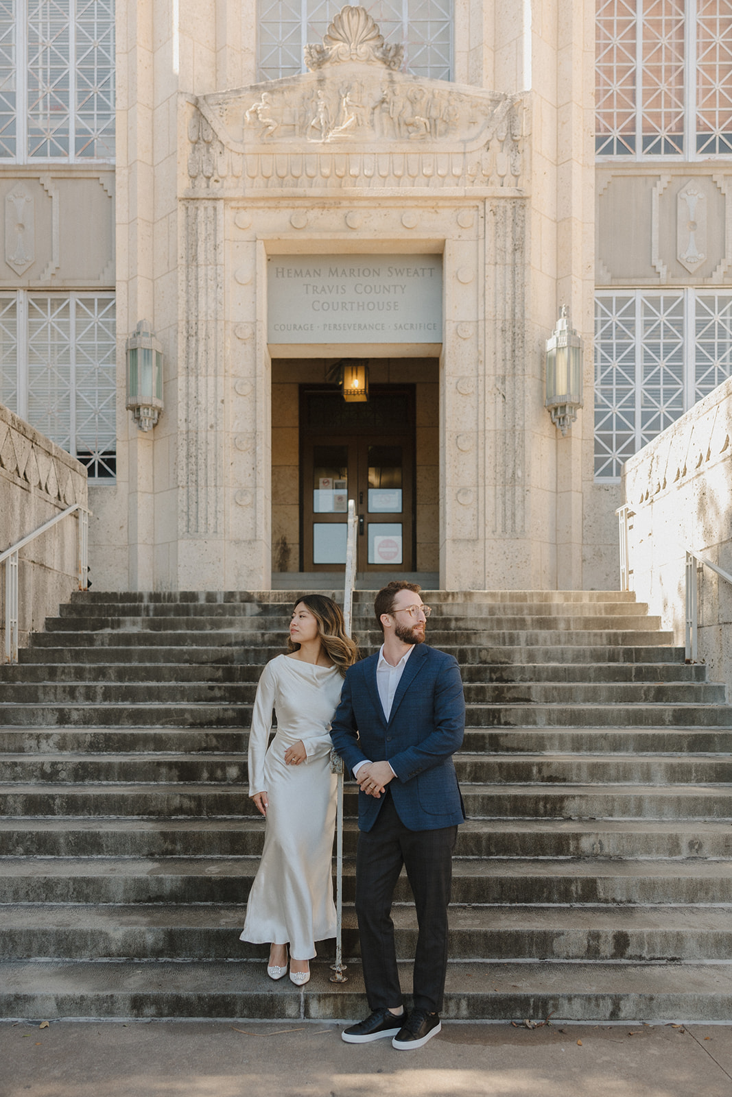 bride and groom standing on the steps outside of the courthouse after their elopement in downtown Austin 