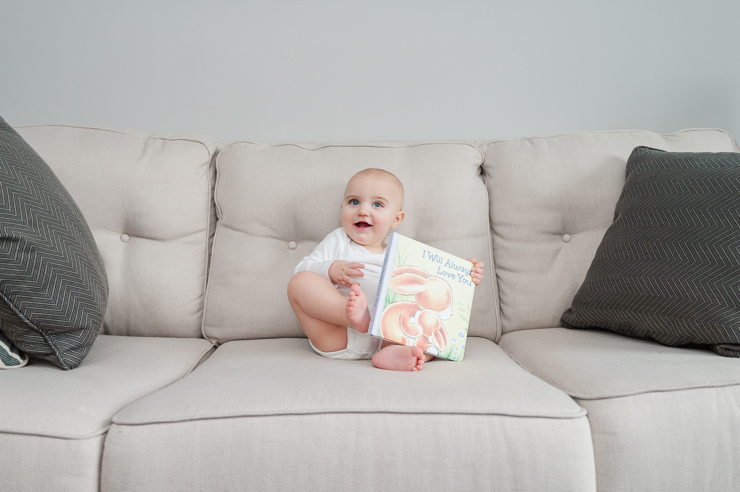 9 month old sitting on the couch with a book