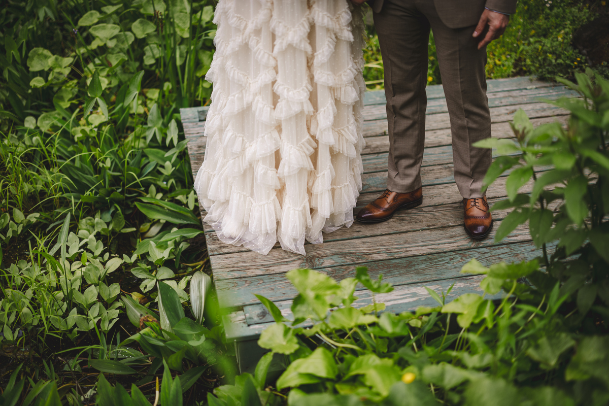 a close up of a bride's dress and a groom's shoes in the Berkshire botanical garden