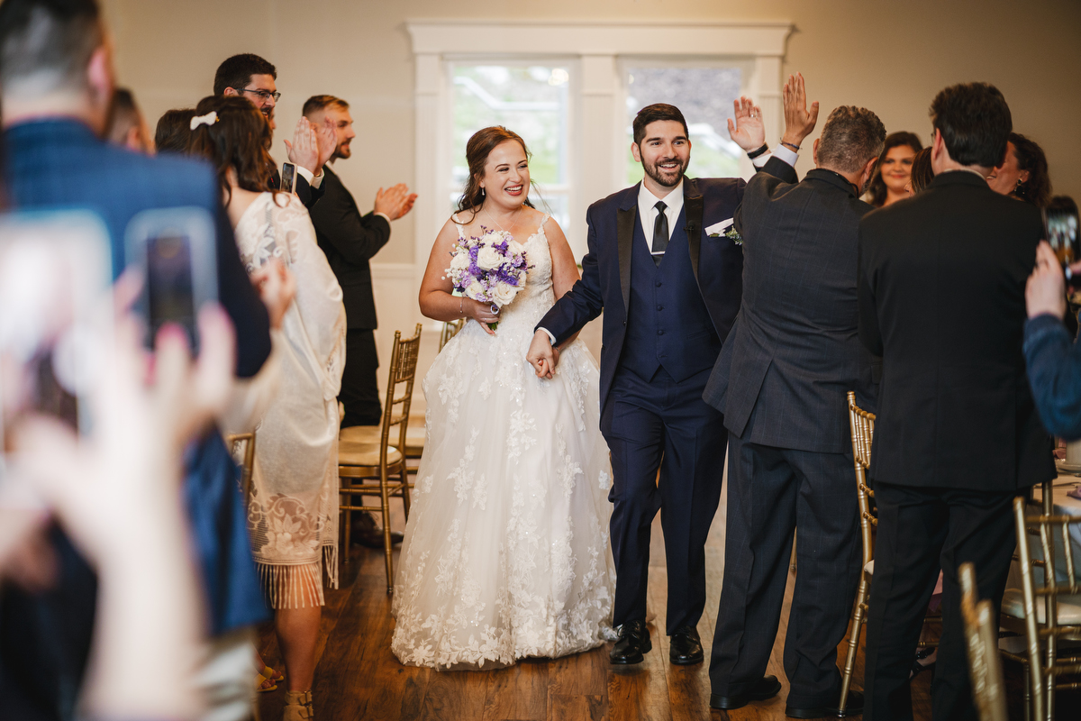 smiling Bride and groom high five guests after wedding ceremony