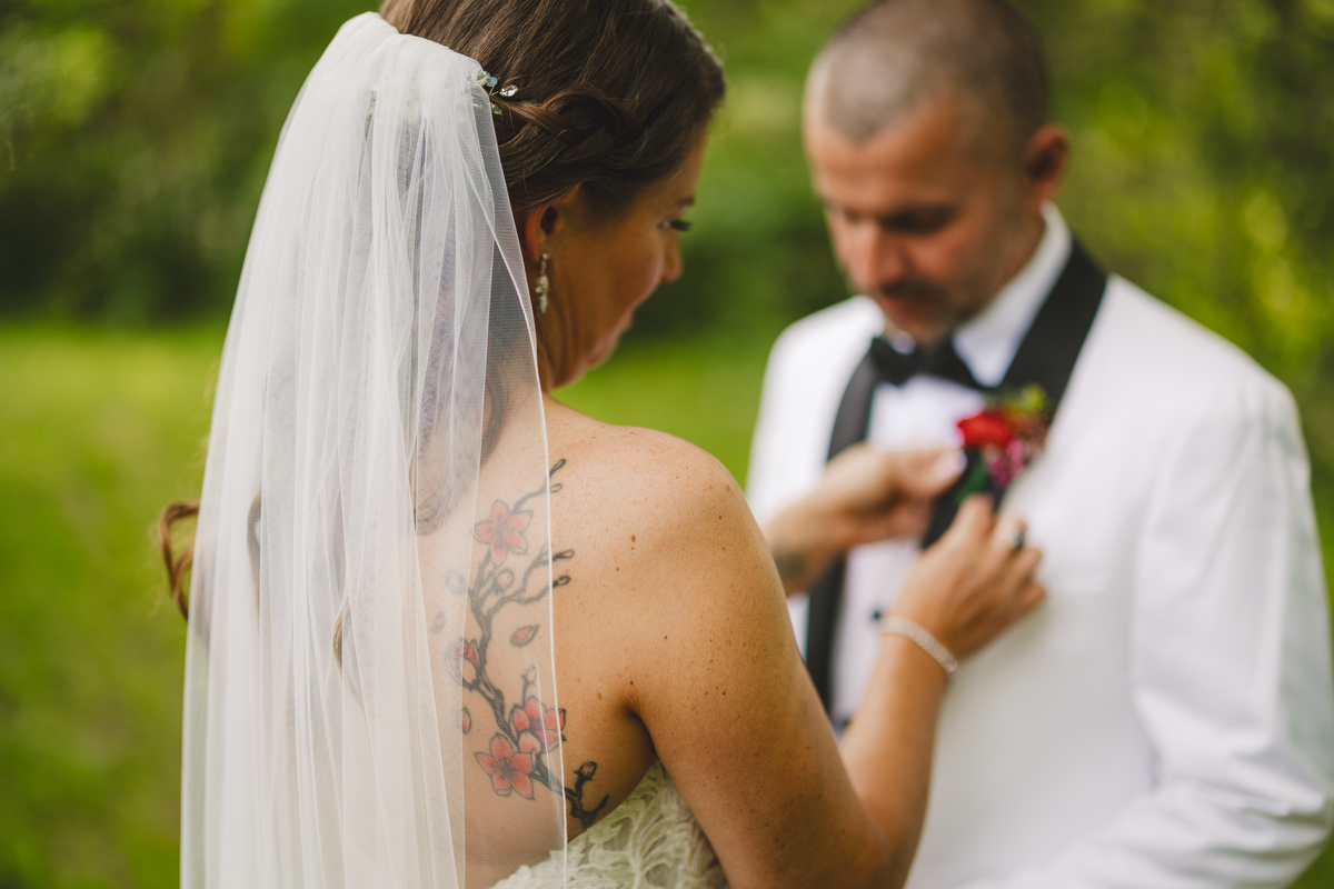 a bride pins a boutonniere on her groom before a wedding at the Montague retreat center 