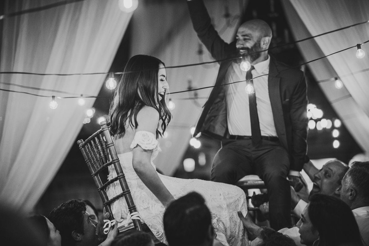 bride and  groom are lifted up on chairs on the dance floor at their quonquont farm wedding reception 