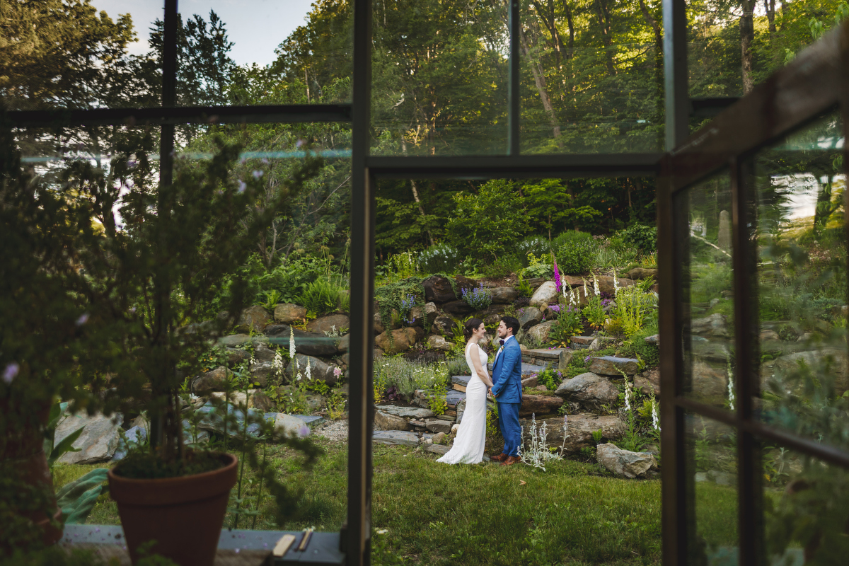 a bride and groom pose in front of the green house at Gloriosa & Co. in Ashfield 