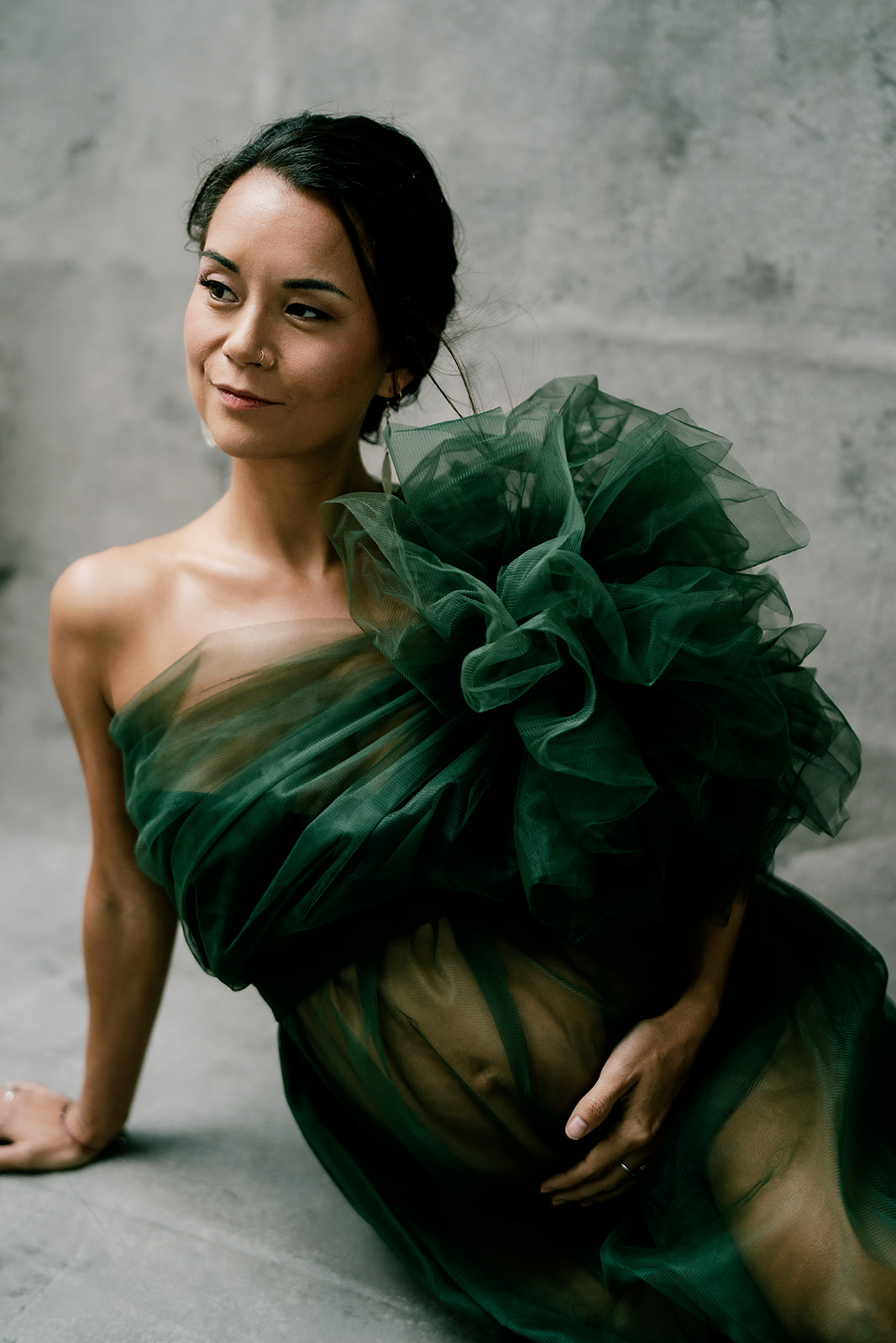 A woman in a green dress posing on a concrete floor.