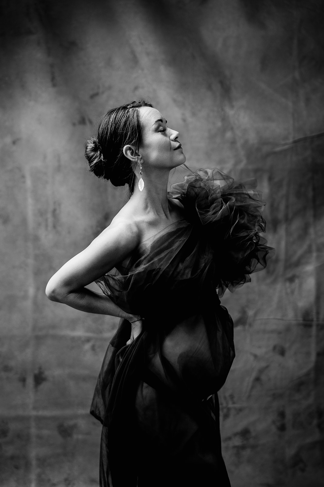 A woman in a tulle dress during her maternity photography studio session.