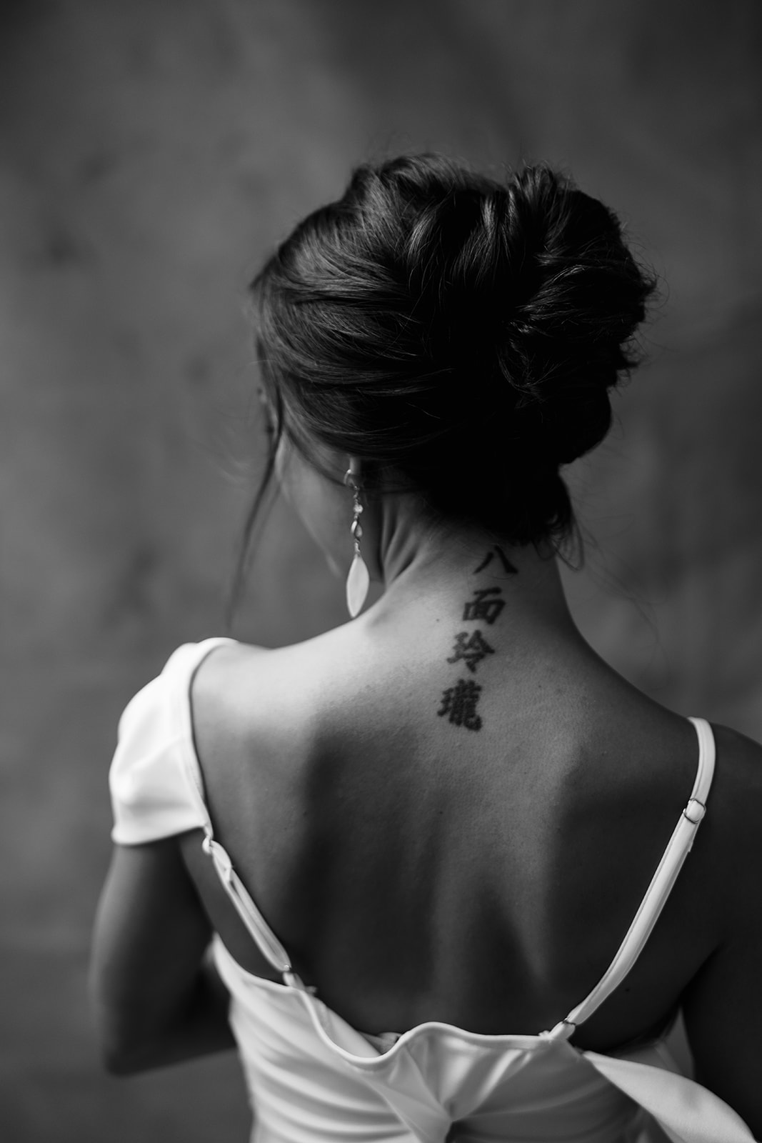A black and white photo of a woman with a tattoo on her back.