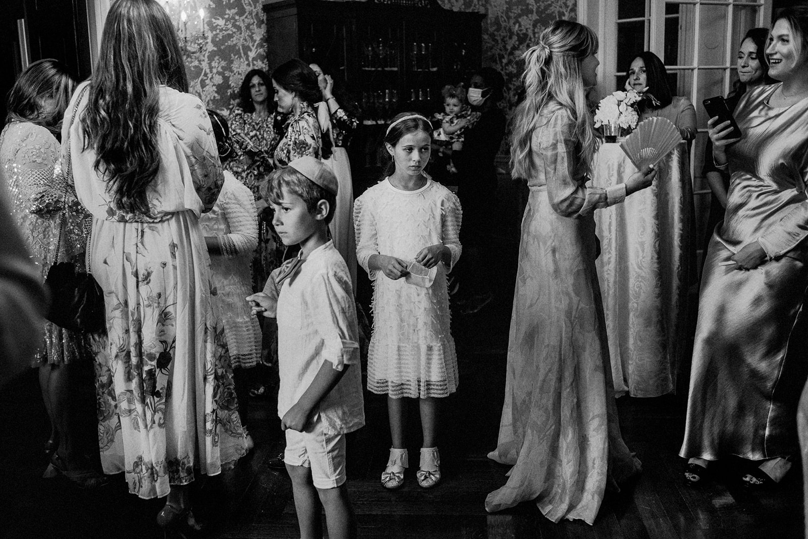 black and white documentary style image of children waiting in crowd of wedding guests