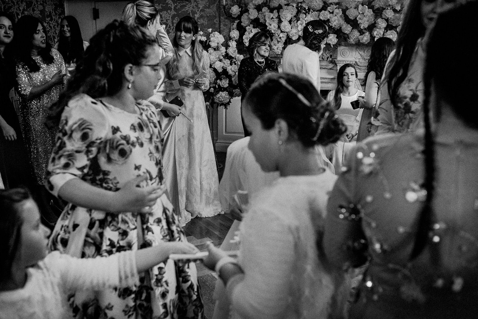 black and white layered image with jewish bride in background sitting in bedeken room and surrounded by guests and child