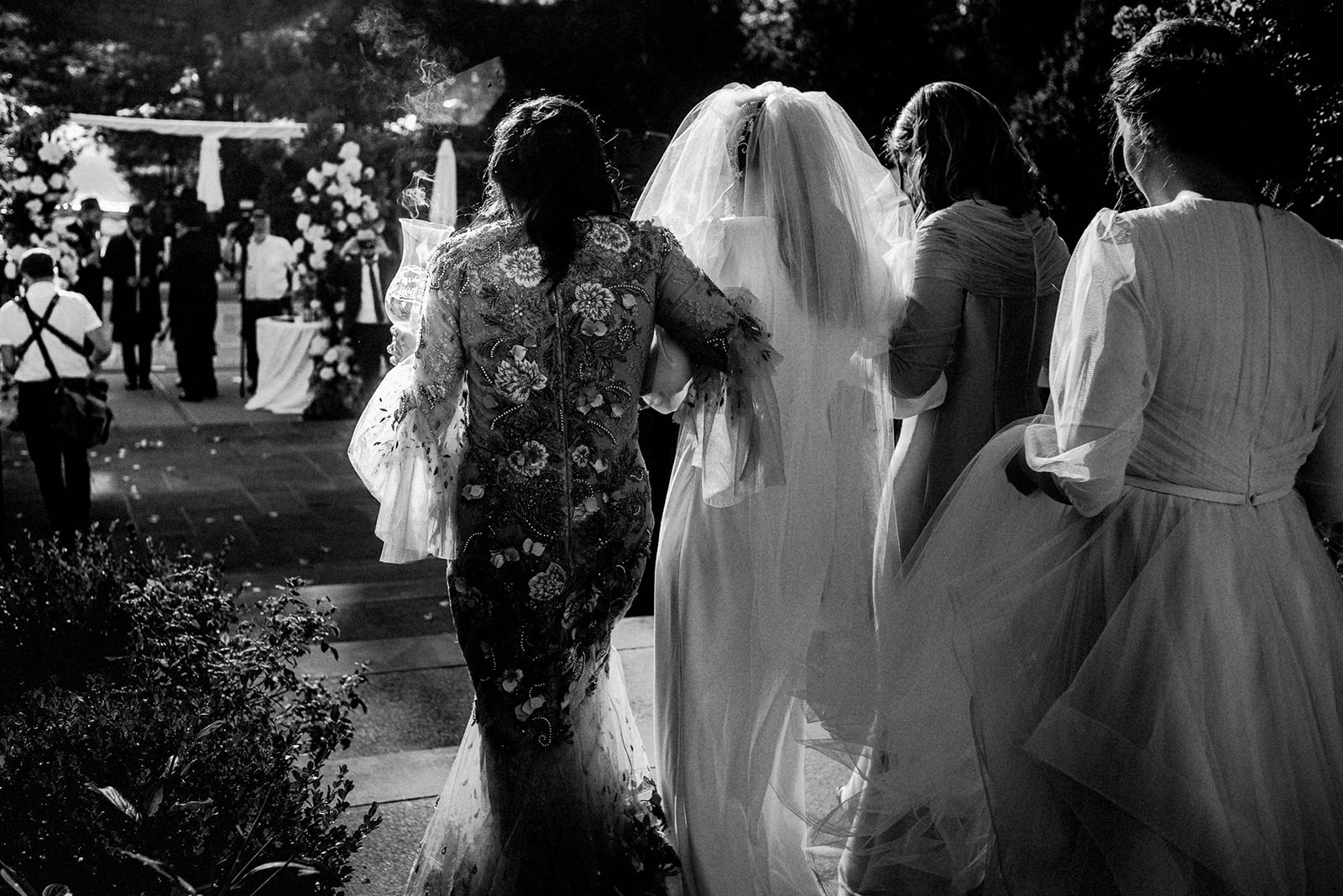 bride beautifully back lit and photographed from behind as she enters the chuppah ceremony