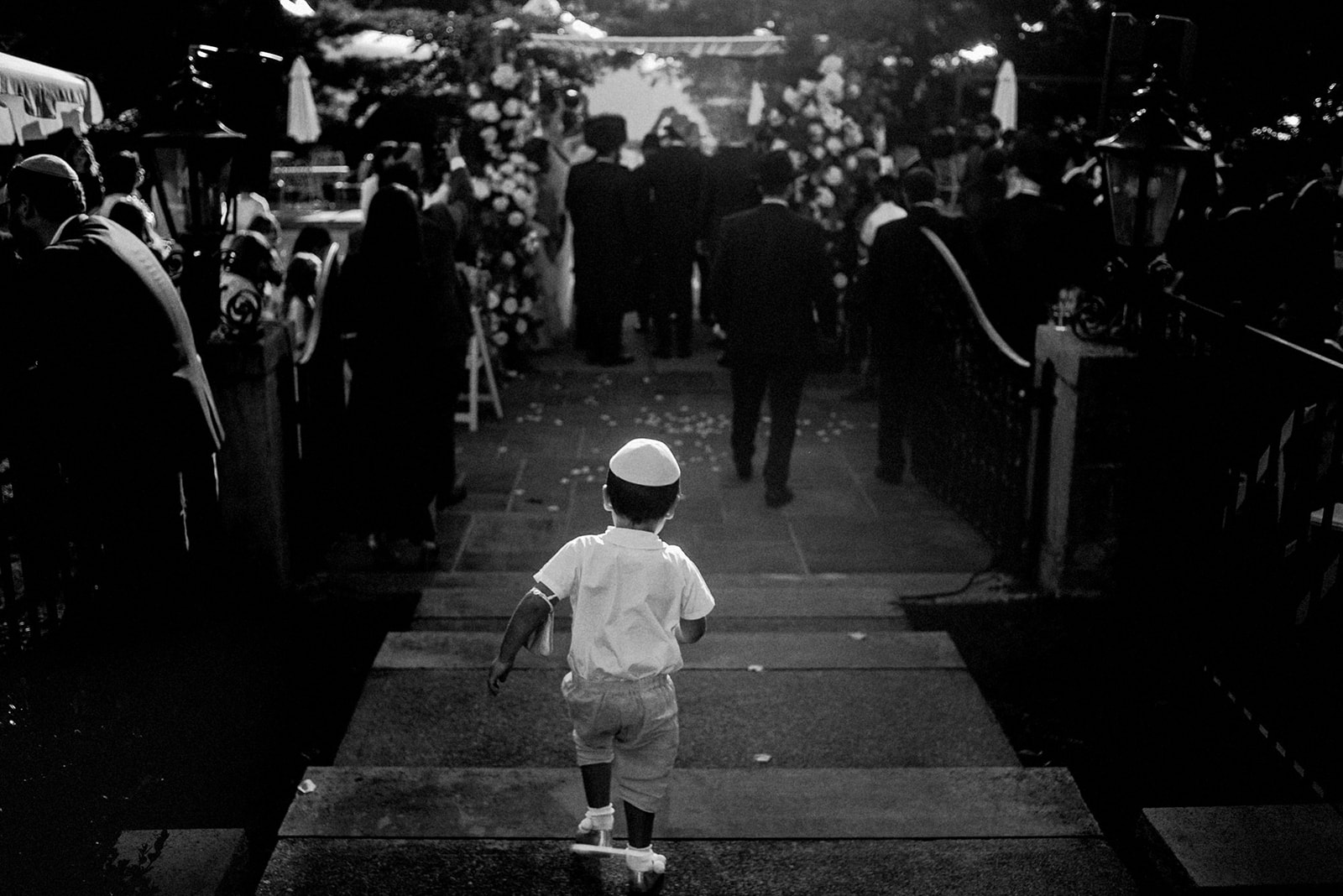 jewish little boy running towards chuppah in black and white image