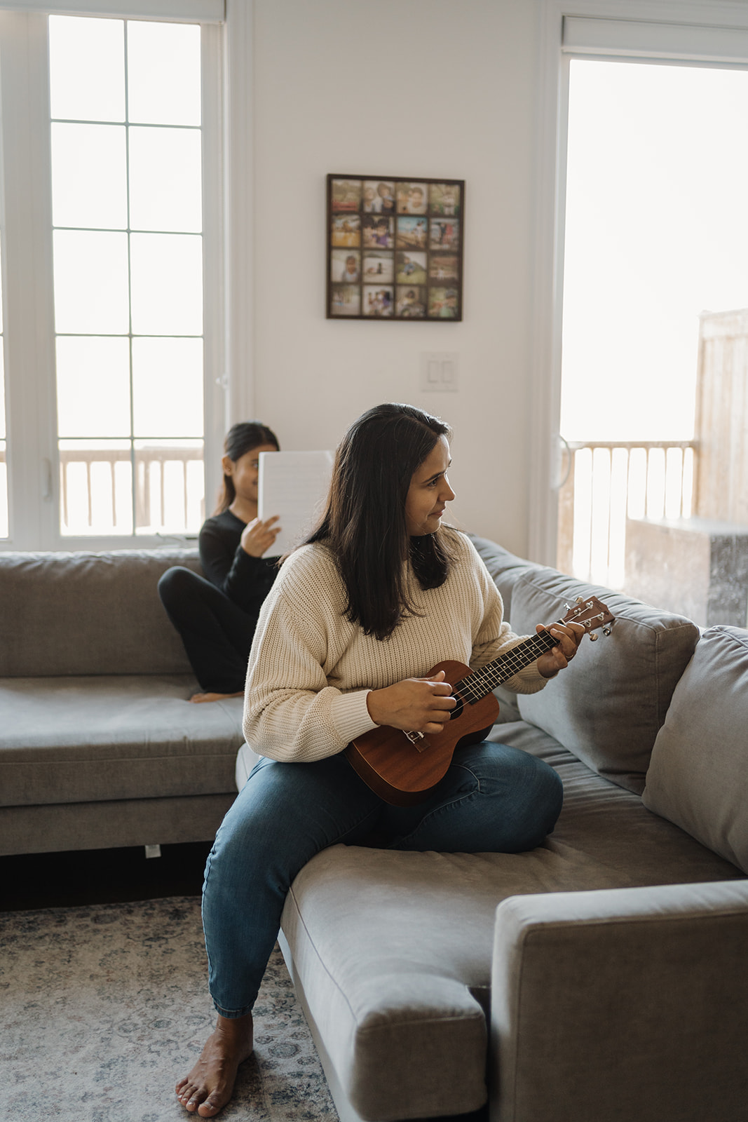 A mother playing the ukulele on the couch.