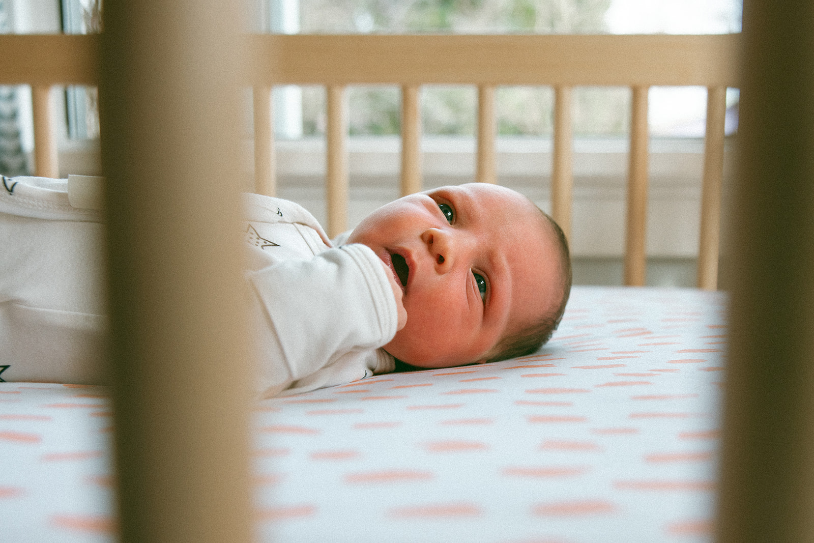 photo of newborn baby laying in crib with eyes open